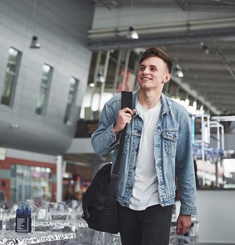 Smiling man walking through airport for Abroad Study Consultancy Kerala